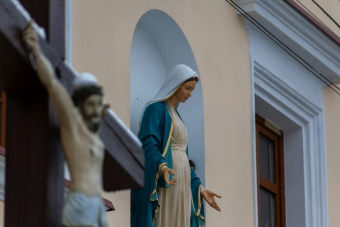 a statue of a person holding a cross in front of a building