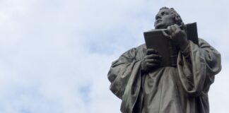 Membongkar Kesesatan Martin Luther Menambahkan “Sola” dalam Kita Suci man holding book statue under white clouds during daytime
